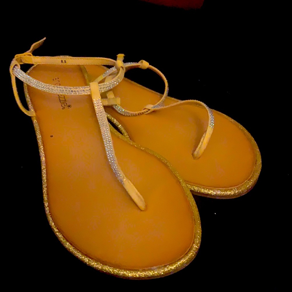 A pair of yellow sparkle sandals.flats
